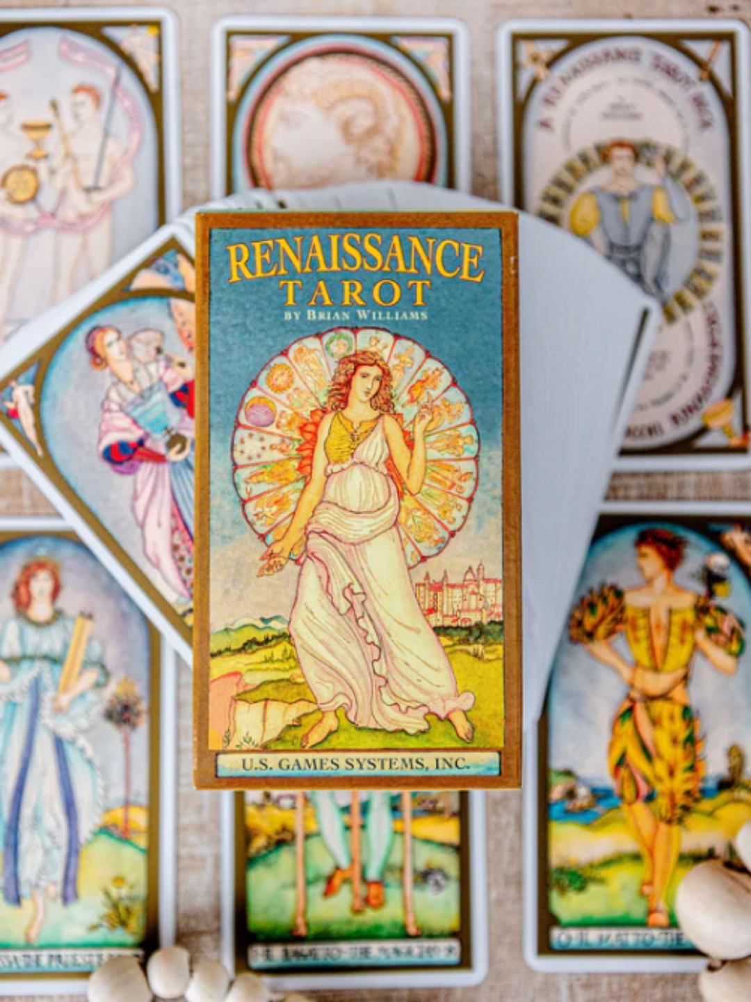 Front cover of the Renaissance Tarot by Brian Williams featuring a red-haired woman in a white Renaissance gown standing on a cliff. A zodiac wheel is behind her, with grassy hills and a distant castle in the background. Smaller sample cards, including The Fool, surround her, creating a warm early-summer palette that fits the Strawberry Moon theme of the seasonal insight and renewal.