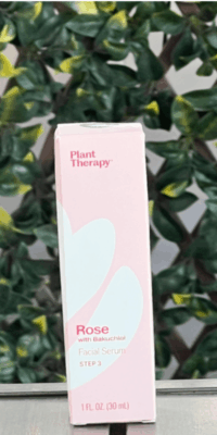 Plant Therapy Rose with Bakuchiol Facial Serum in light pink packaging with a white floral design, labeled Step 3, displayed on an outdoor table with lattice and ivy leaves in the background.