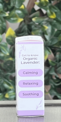 Side of Plant Therapy Organic Lavender Pure Essential Oil box in white packaging with purple trim, shown outdoors on a table with lattice and ivy in the background. The side panel features lavender illustrations at the top and bottom, and text that reads 'Get to Know Organic Lavender" with three stacked oblong purple shapes labeled "Calming", "Relaxing", "Soothing".