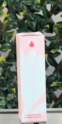 Side panel of Plant Therapy Rose with Bakuchiol Facial Serum box in light pink packaging with a dark pink water drop icon at the top and the phrase "Extract more from life's little moments' at the bottom, shown outdoors on a table with lattice and ivy in the background.