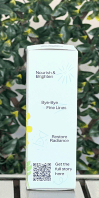 Side of Plant Therapy Younger Glo Facial Oil box in white packaging, displayed outdoors on a table with lattice and icy in the background. The side panel features text reading "Nourish & Brighten'" Bye-Bye Fine Lines", and "Restore Radiance", a squiggly line through "Bye-Bye Fine Lines", and a QR code at the bottom labeled "Get the full story here" with a squiggly arrow pointing to it.