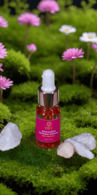OYU Botanica Bakuchiol Booster Serum bottle displayed among crystals, with small pink flowers rising from the surface in the background, creating a natural, serene skincare scene.